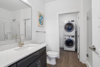 A bathroom with a toilet sink and a washing machine    and a laundry
